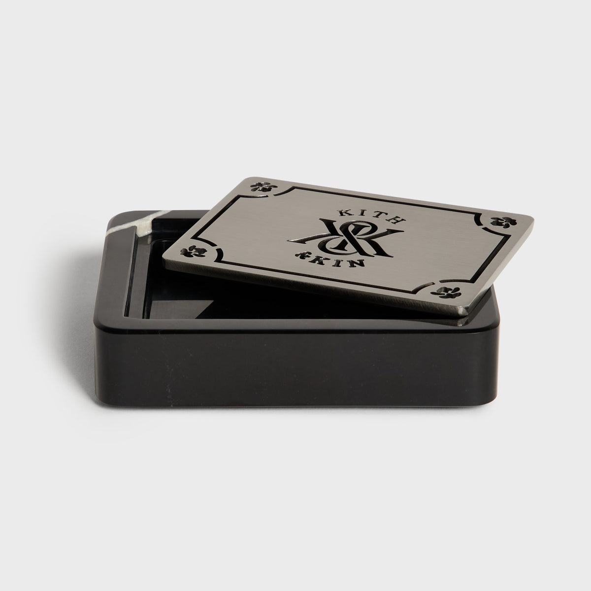 Open black marble Kith soap dish with the metal lid set beside it