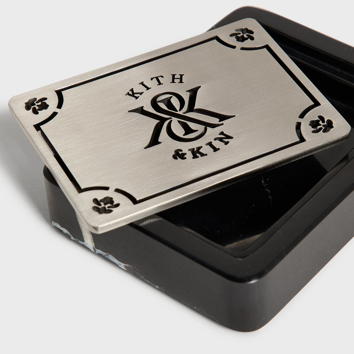 Close-up of the metal 'Kith & Kin' lid on the black marble soap dish