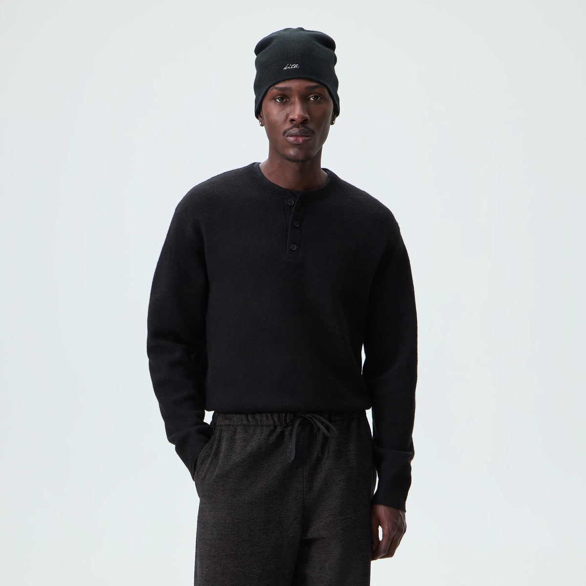 Man wearing black Kith Harmon knit henley sweater with a beanie, front view