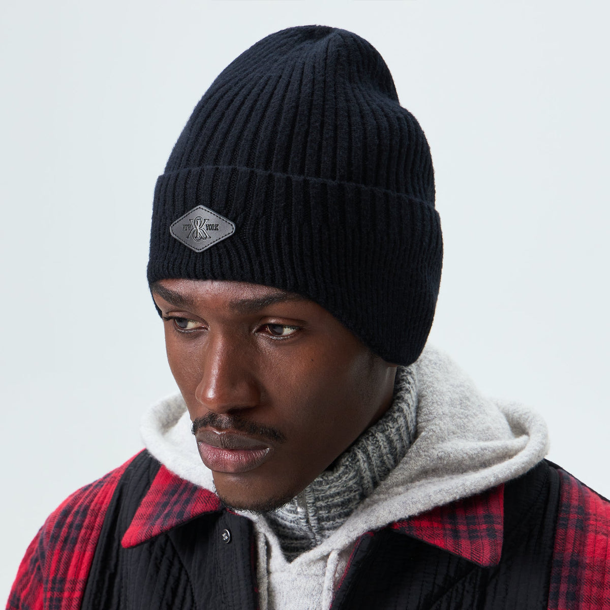 Man wearing black Kith chunky knit earflap beanie, front view