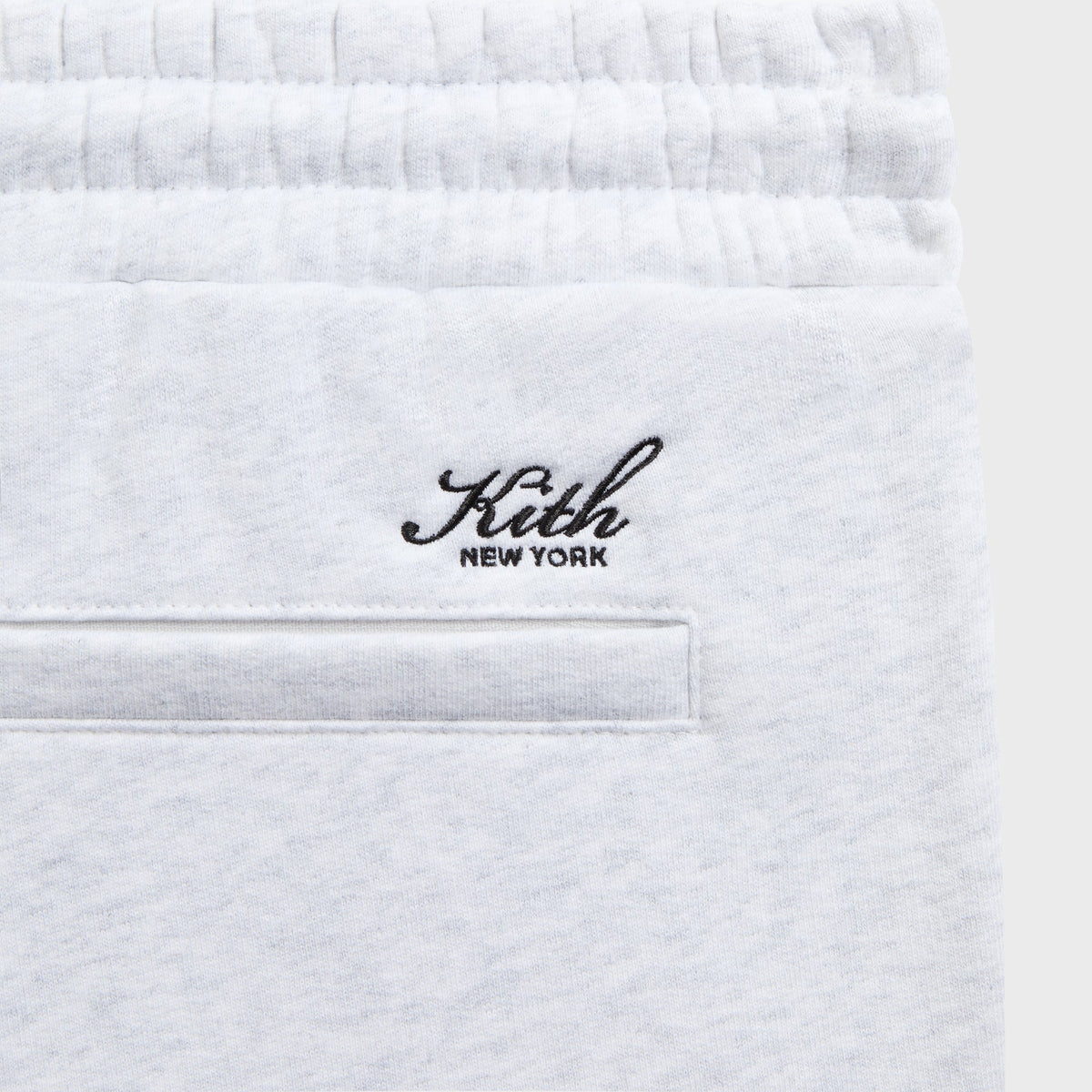 Close-up of the black 'Kith New York' script above the welt pocket on the grey Bryson sweatpant