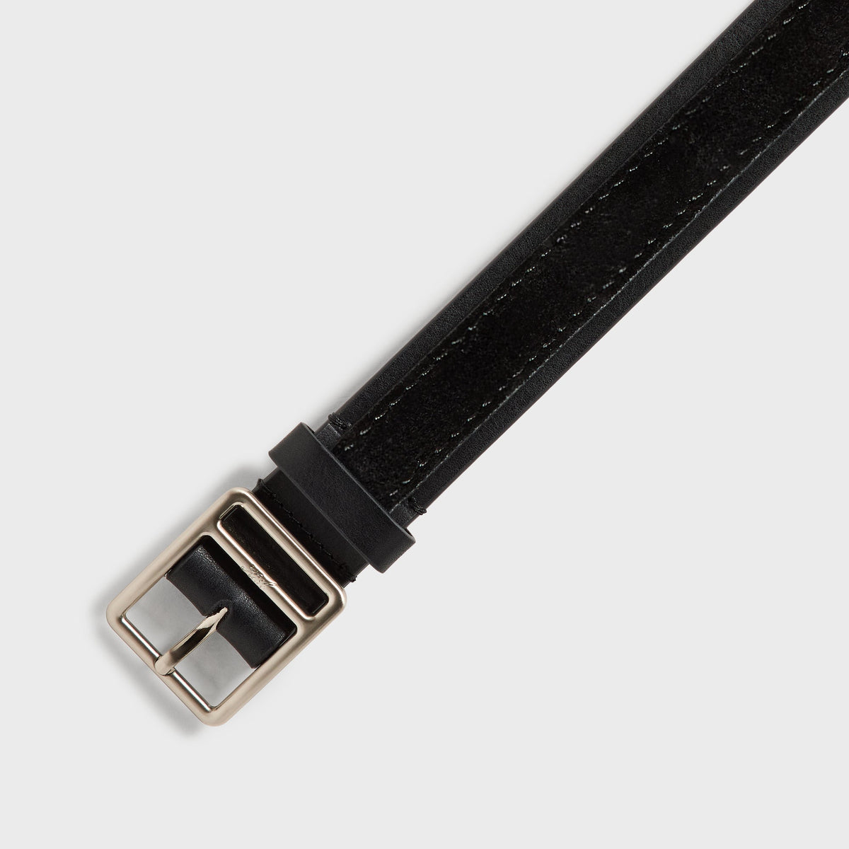 Close-up of the ornate silver buckle and strap tip on the black two-tone belt